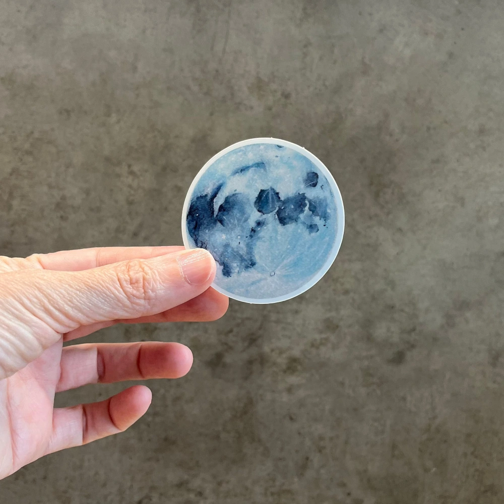 Watercolor full moon vinyl sticker held in hand