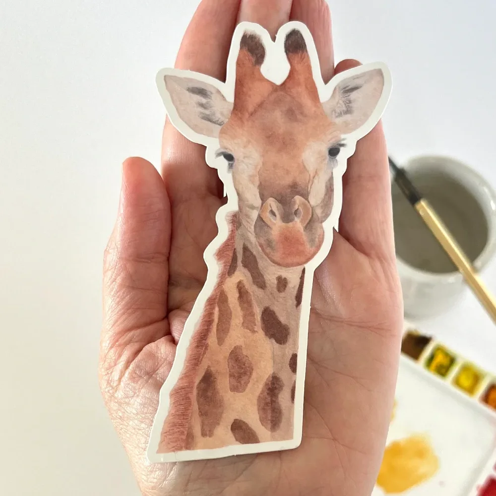 Hand-painted watercolor giraffe vinyl sticker held in hand