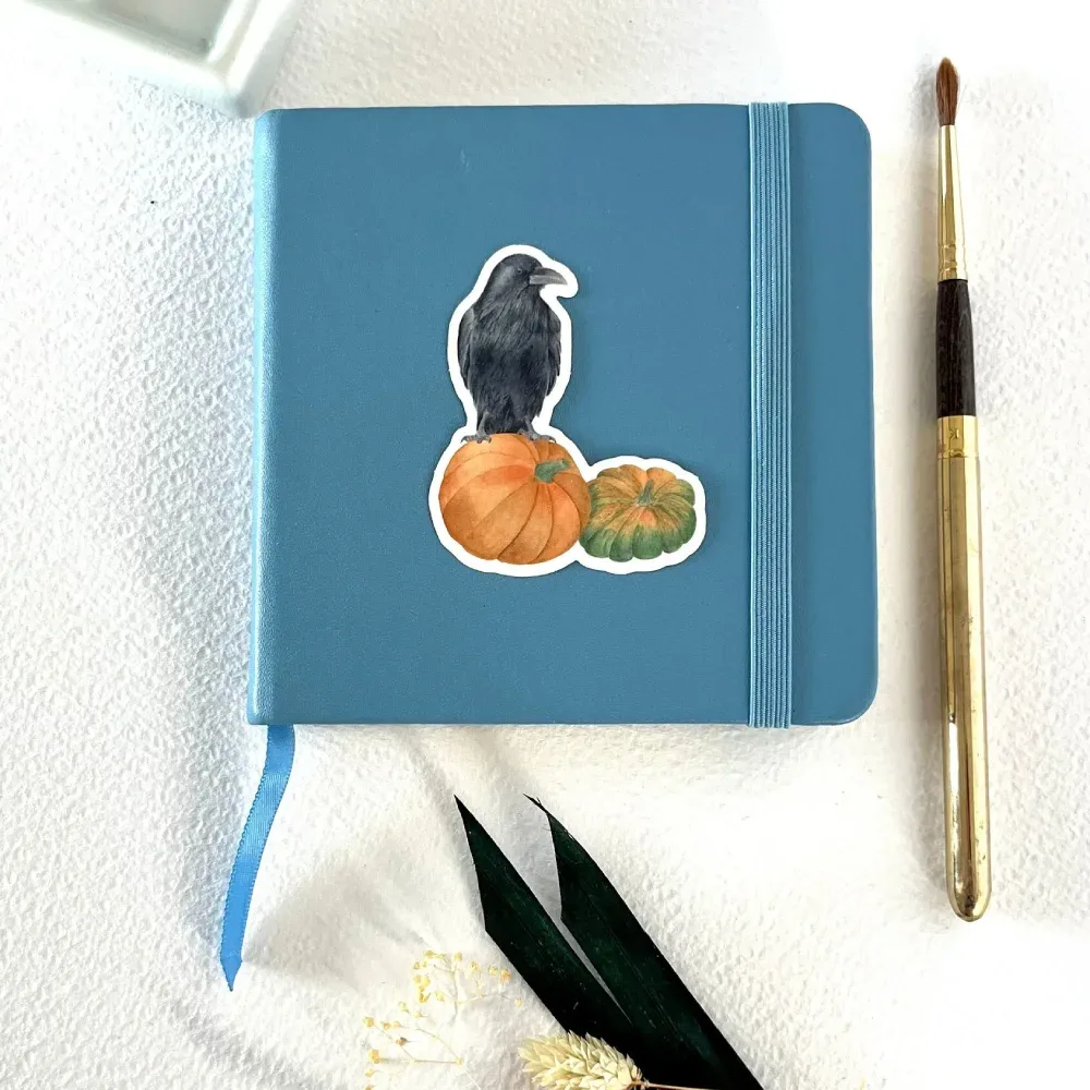 Raven on pumpkins vinyl sticker on notebook