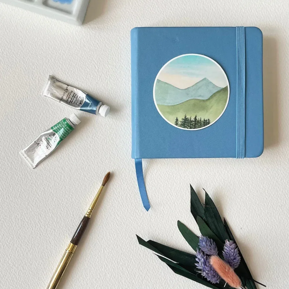 Watercolor mountain landscape vinyl sticker on notebook