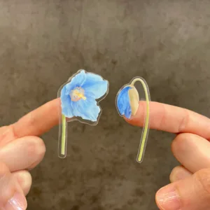 Hand-painted Watercolor Blue poppy stickers for laptop held in hand